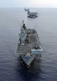 The UK Royal Navy Invincible-class aircraft carrier HMS Illustrious, and Nimitz-class aircraft carriers USS Harry S Truman and USS Dwight D Eisenhower transit in formation during a multi-ship maneuvering exercise in the Atlantic Ocean